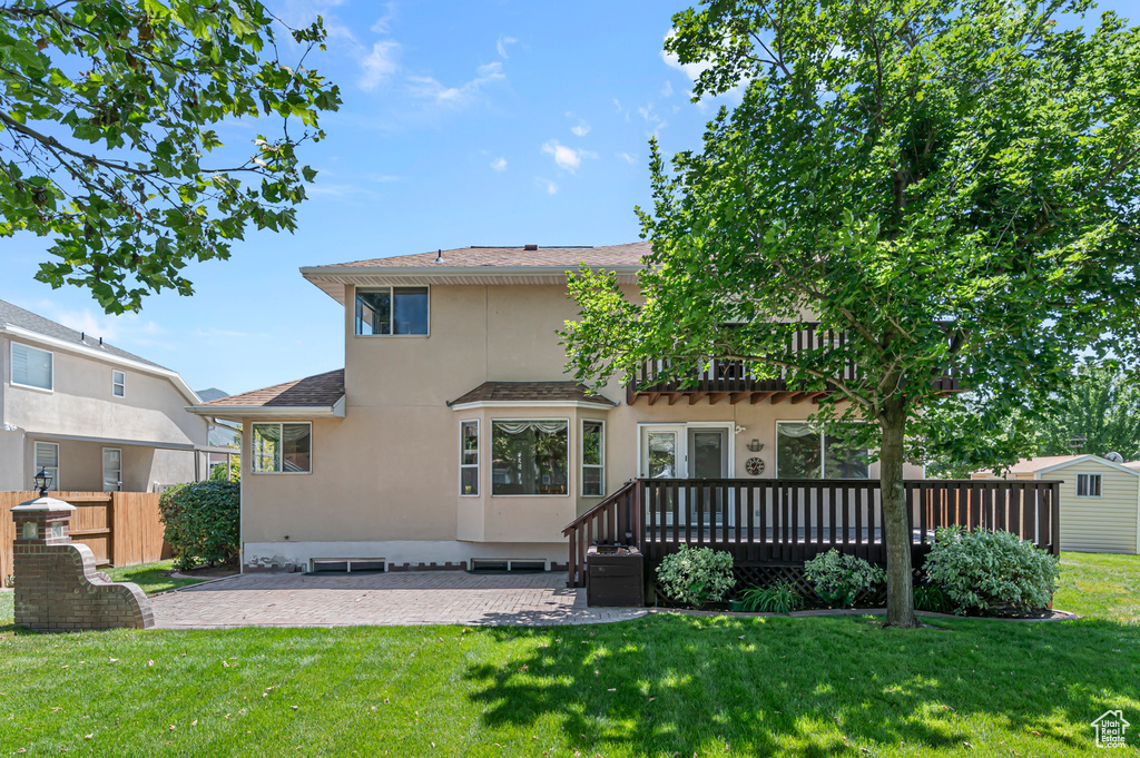 Back of property with stucco siding, a patio, a deck, and a shingled roof