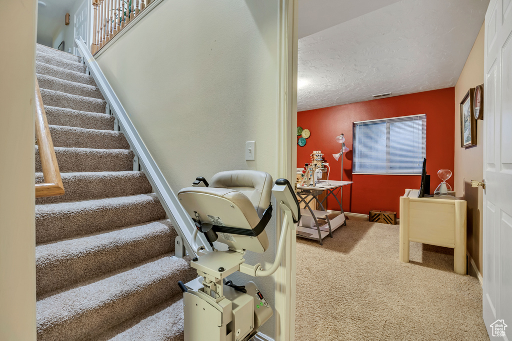 Stairs with carpet and a textured ceiling