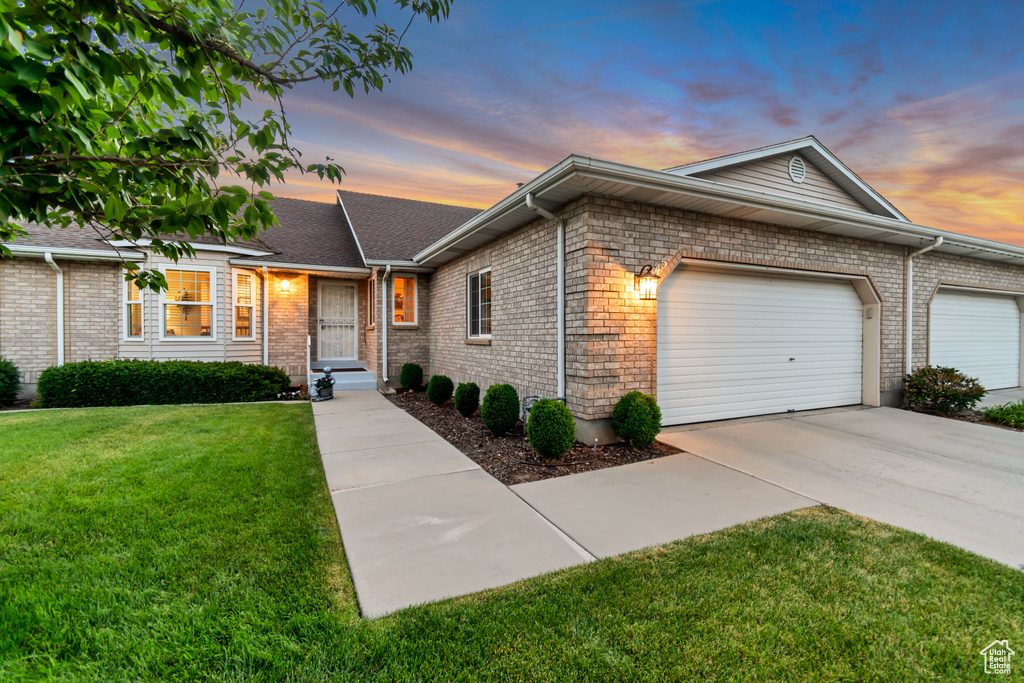 View of front facade featuring a front yard, an attached garage, concrete driveway, and brick siding