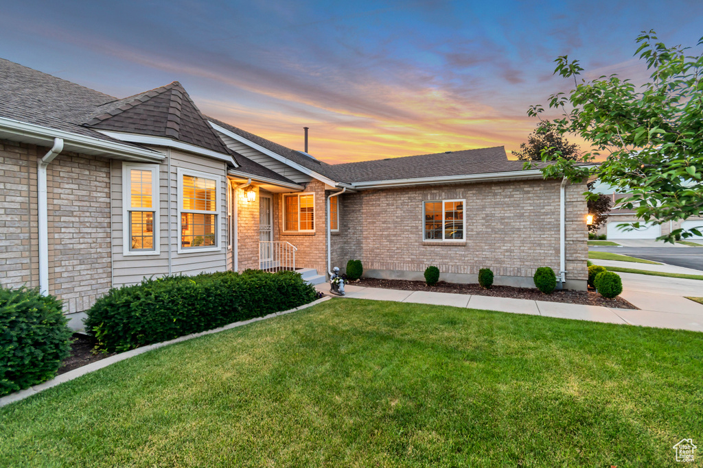 Ranch-style home featuring a front lawn, a shingled roof, and brick siding
