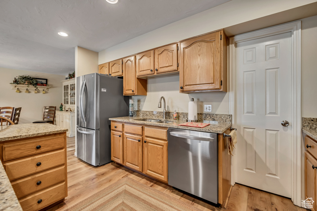 Kitchen featuring appliances with stainless steel finishes, light wood-style floors, light stone countertops, and recessed lighting