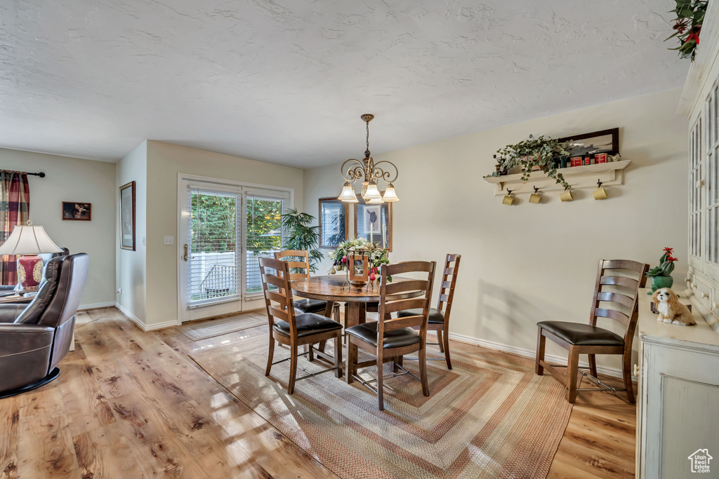 Dining room with a chandelier, light wood-type flooring, and a textured ceiling