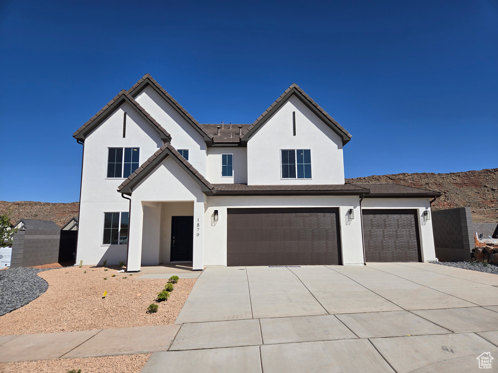 View of front facade with a garage, driveway, stucco siding, and a mountain view