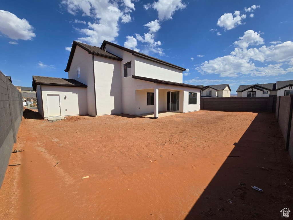 Rear view of house featuring stucco siding, a fenced backyard, and a patio area