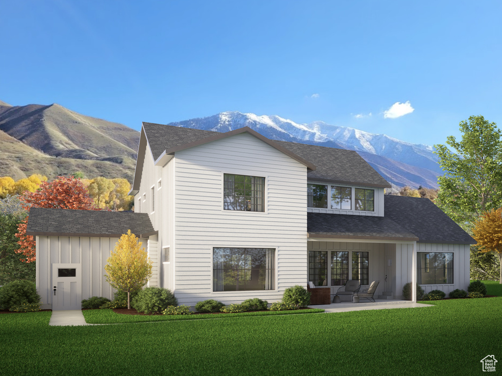 Back of property featuring board and batten siding, a mountain view, a patio area, a yard, and roof with shingles