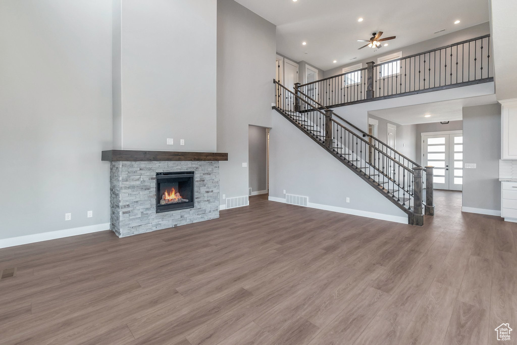 Unfurnished living room featuring a high ceiling, a ceiling fan, stairs, recessed lighting, and wood finished floors