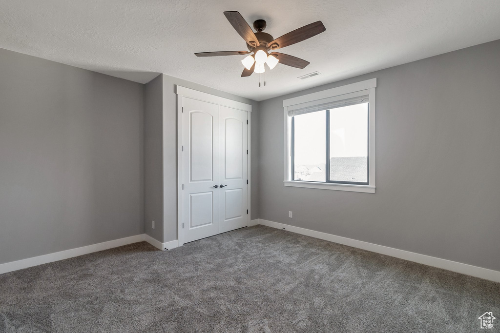 Unfurnished bedroom with carpet, a closet, and ceiling fan