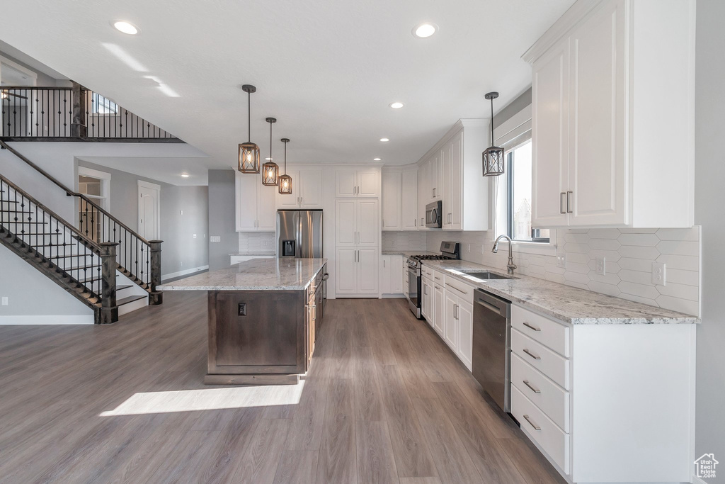 Kitchen featuring stainless steel appliances, wood finished floors, recessed lighting, tasteful backsplash, and a kitchen island