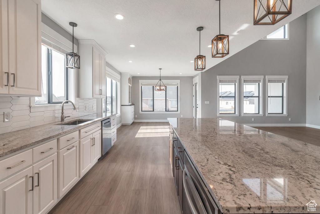 Kitchen featuring dishwasher, a chandelier, tasteful backsplash, recessed lighting, and white cabinetry