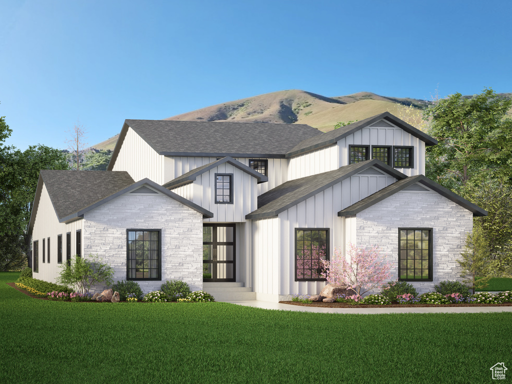 Modern farmhouse style home featuring a shingled roof, a front yard, stone siding, and board and batten siding
