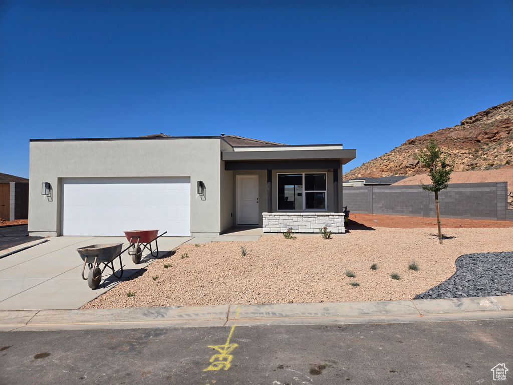 View of front of home with concrete driveway, an attached garage, stucco siding, and a mountain view