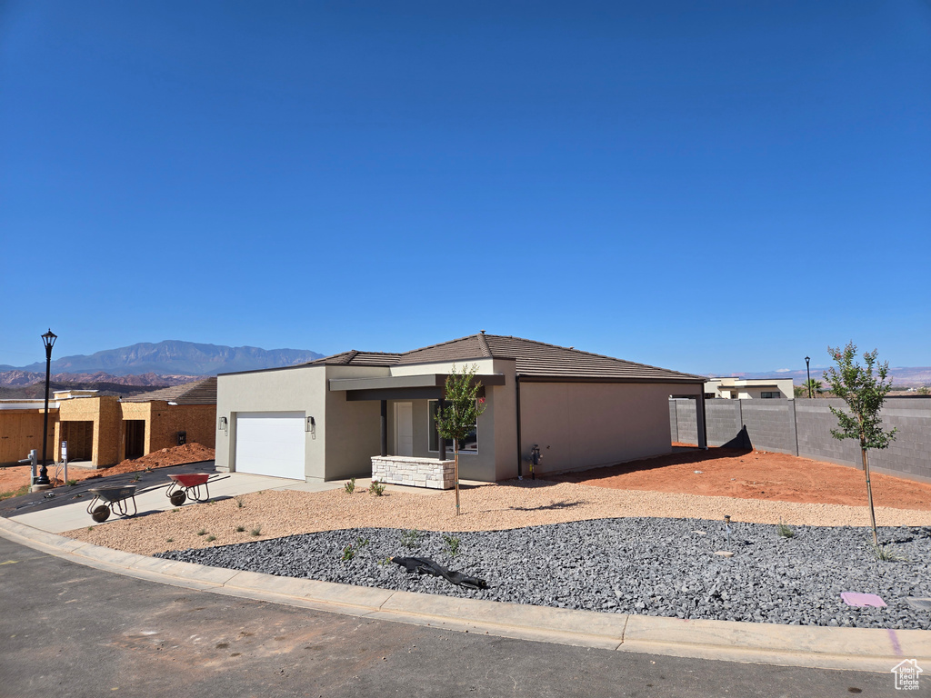 View of front of house featuring stucco siding, a garage, a mountain view, and concrete driveway