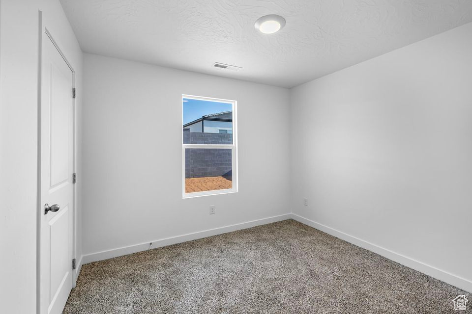 Carpeted spare room featuring baseboards and a textured ceiling