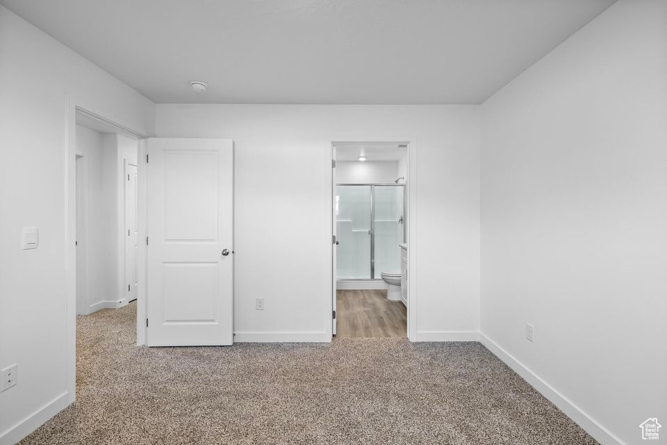 Unfurnished bedroom with carpet flooring and connected bathroom
