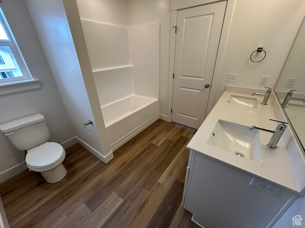 Bathroom featuring double vanity, wood finished floors, and shower / bathtub combination
