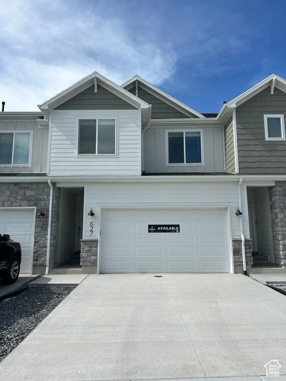 View of property with stone siding, board and batten siding, an attached garage, and driveway