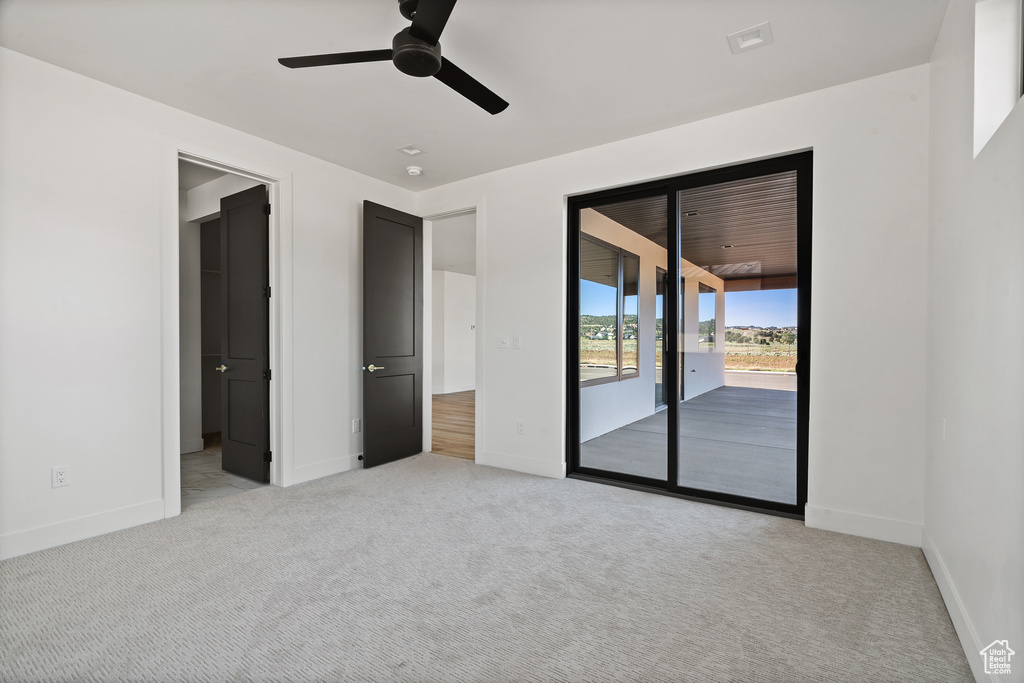 Unfurnished bedroom with access to exterior, light colored carpet, and a ceiling fan