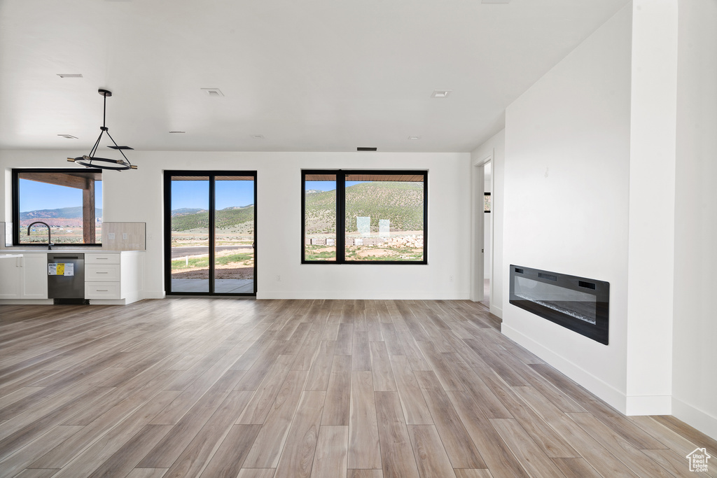 Unfurnished living room with light wood-style flooring and baseboards