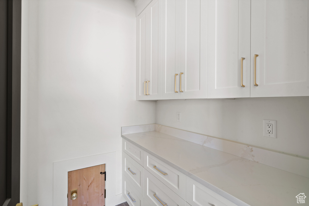 Kitchen with white cabinetry and light stone counters