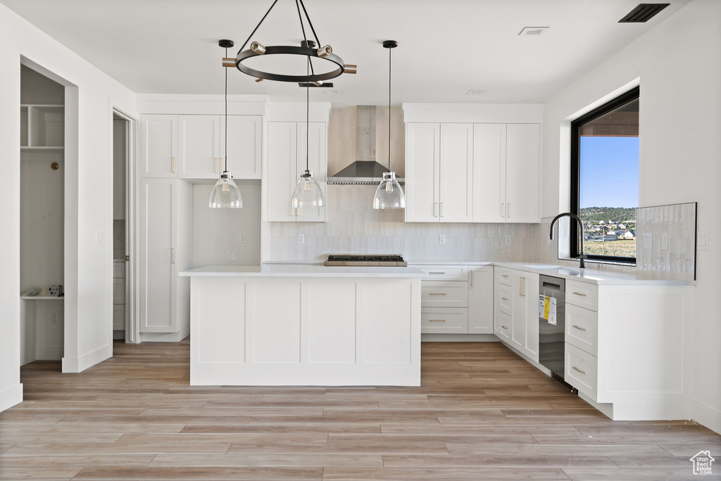 Kitchen featuring wall chimney exhaust hood, decorative backsplash, and light countertops