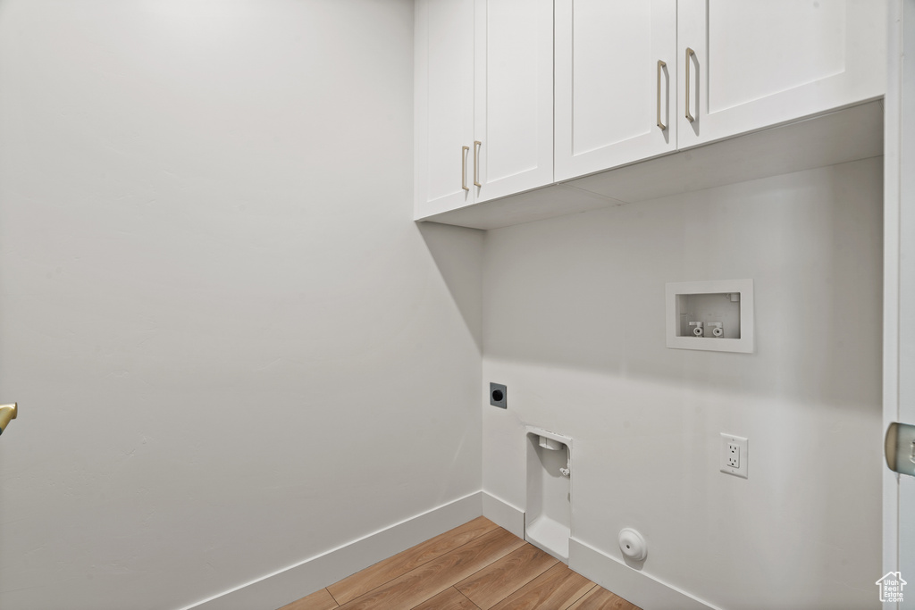 Washroom featuring cabinet space, electric dryer hookup, hookup for a washing machine, light wood-style floors, and gas dryer hookup