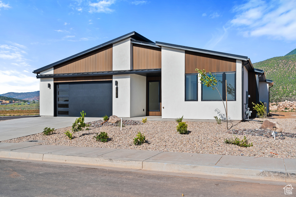 View of front of property with an attached garage, a mountain view, and driveway