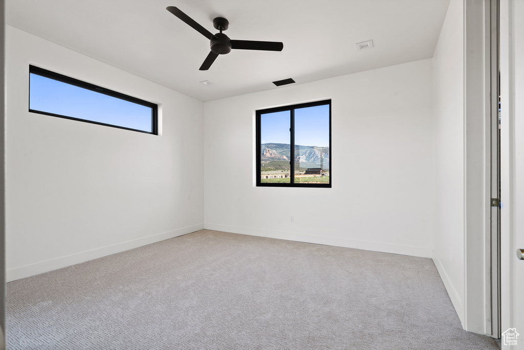 Carpeted empty room with a ceiling fan and baseboards