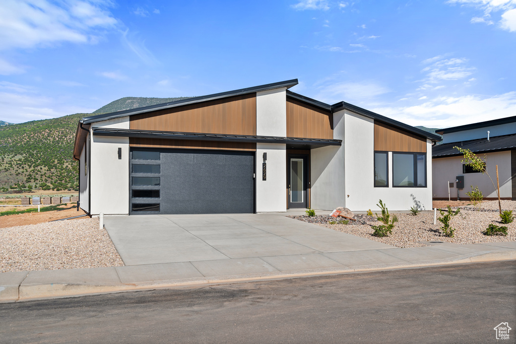 Contemporary house with an attached garage, concrete driveway, and a mountain view