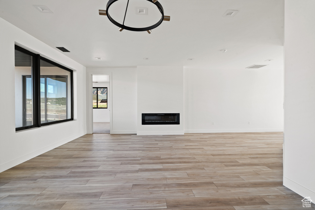 Unfurnished living room featuring light wood-type flooring and a glass covered fireplace