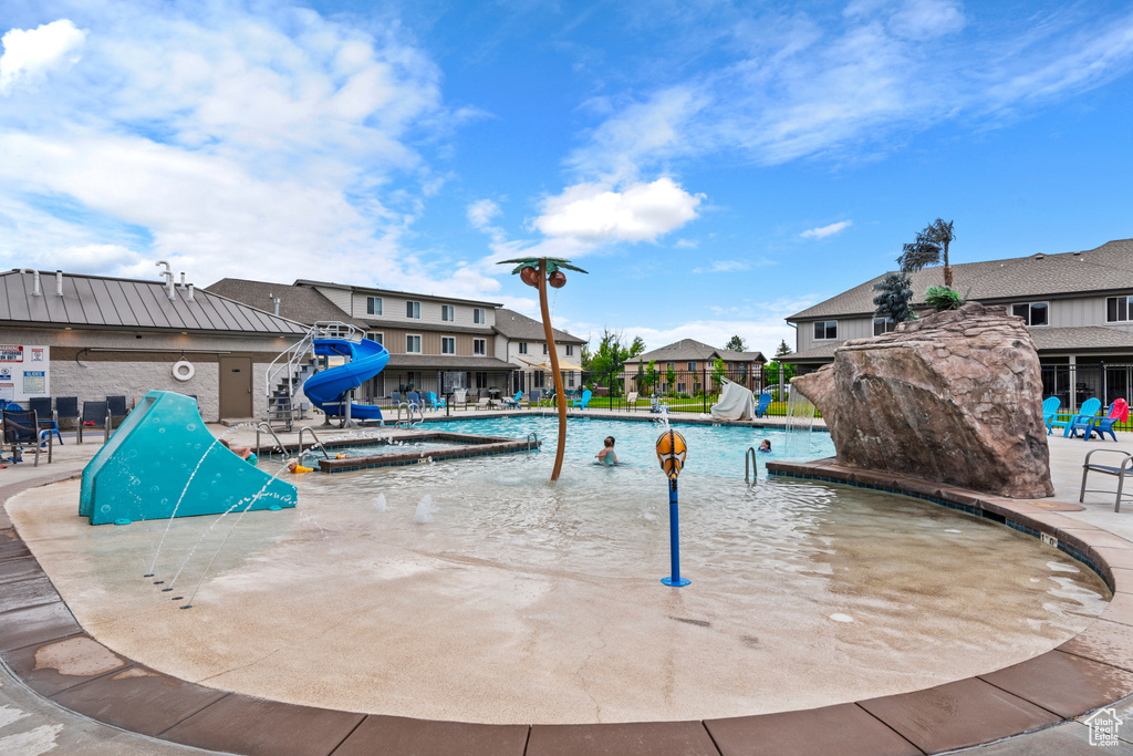 Community pool featuring a residential view, a water slide, and a patio area
