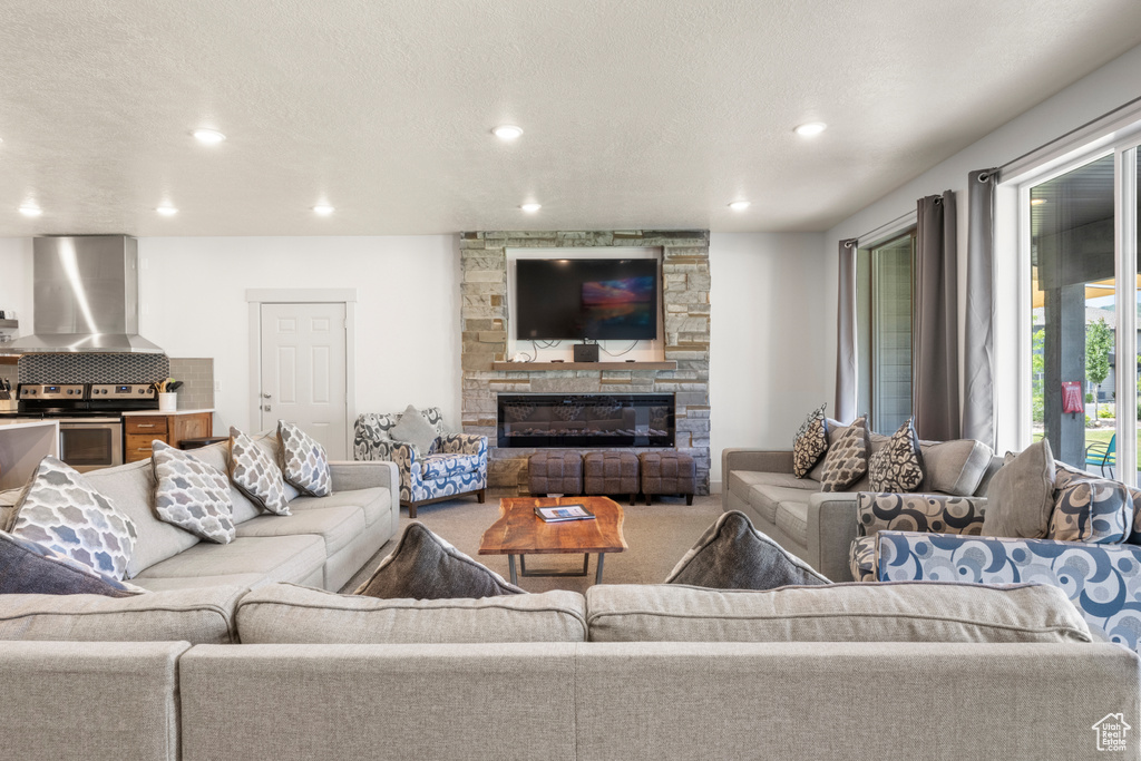 Living area featuring a stone fireplace, recessed lighting, and carpet flooring