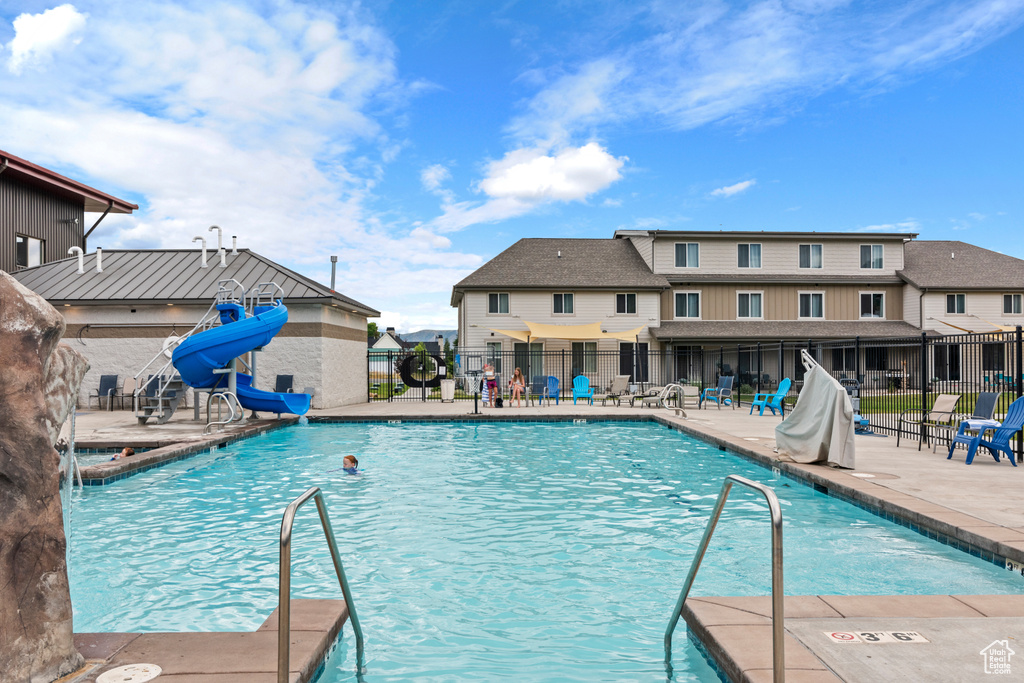 Community pool with a patio and a water slide