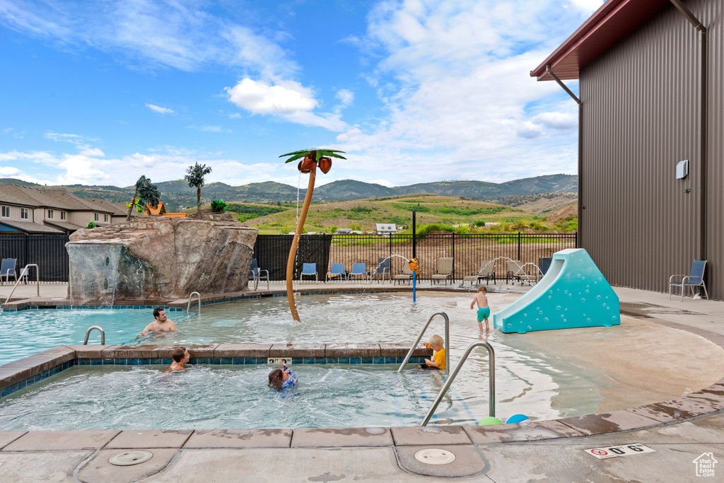 Community pool featuring a mountain view, a patio area, and a hot tub