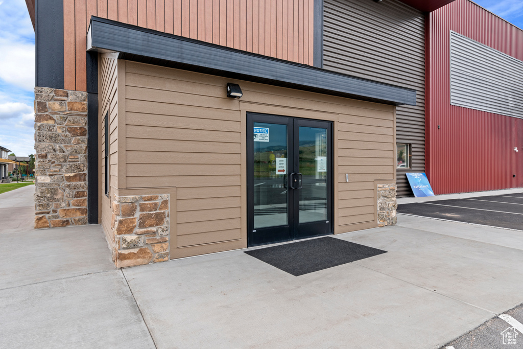 Doorway to property with stone siding, french doors, and uncovered parking