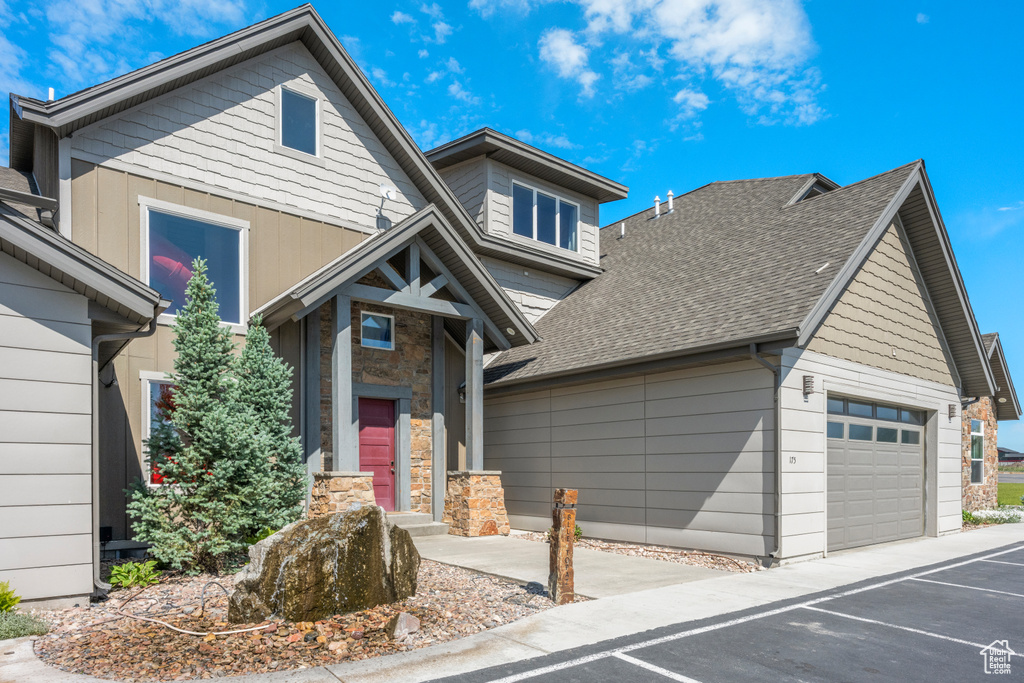 Craftsman inspired home featuring stone siding and a shingled roof