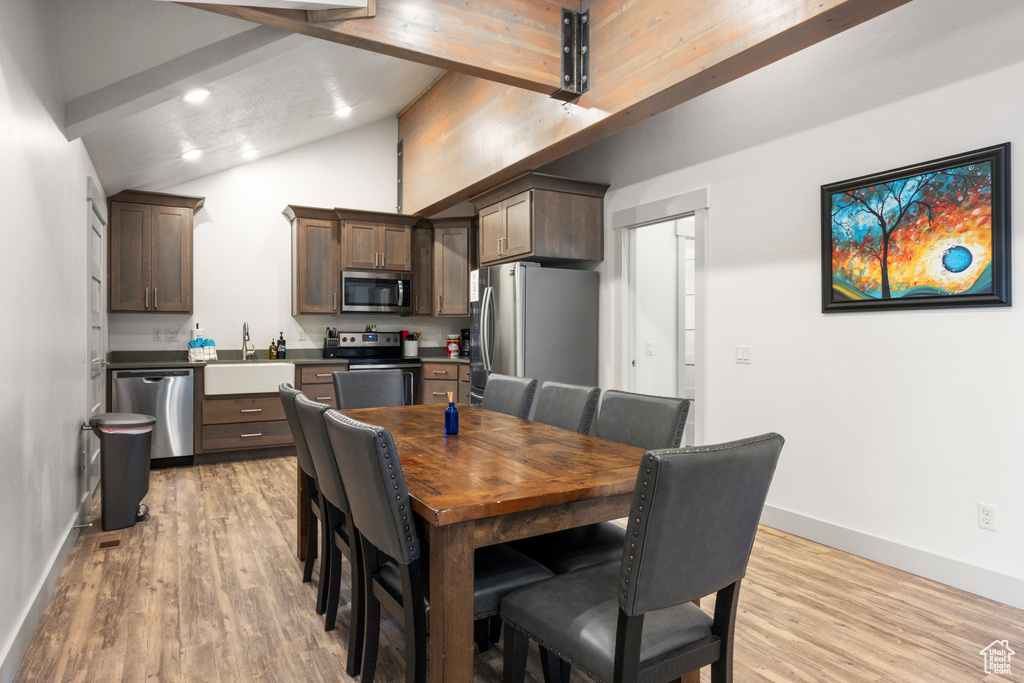 Dining room with light wood-style floors, recessed lighting, beam ceiling, and high vaulted ceiling