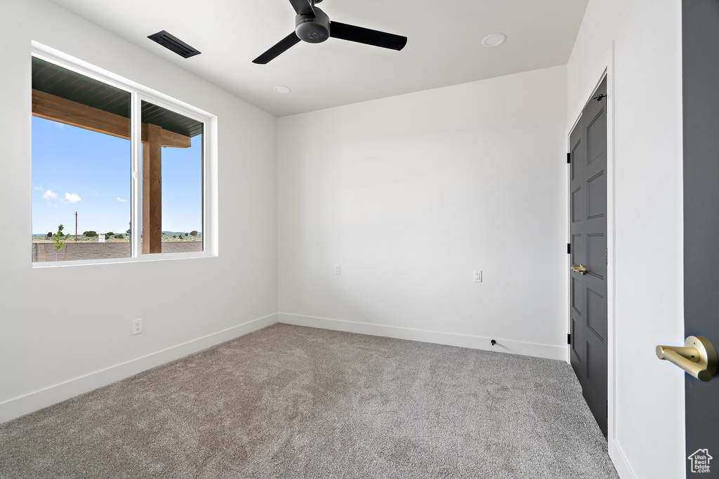 Carpeted empty room featuring ceiling fan and baseboards