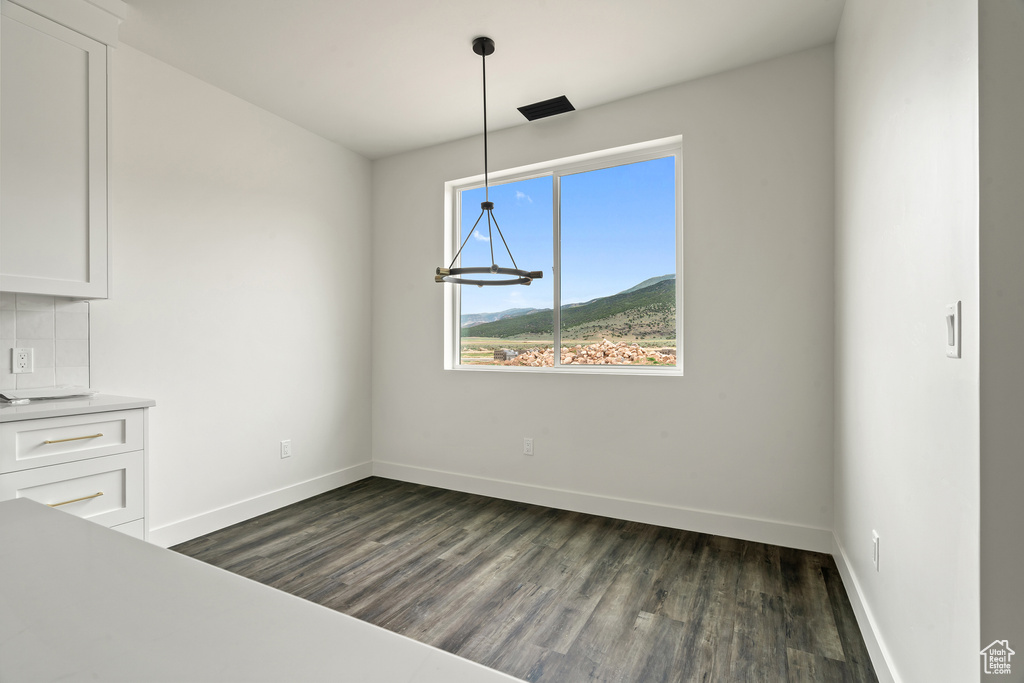 Unfurnished dining area with dark wood-style flooring
