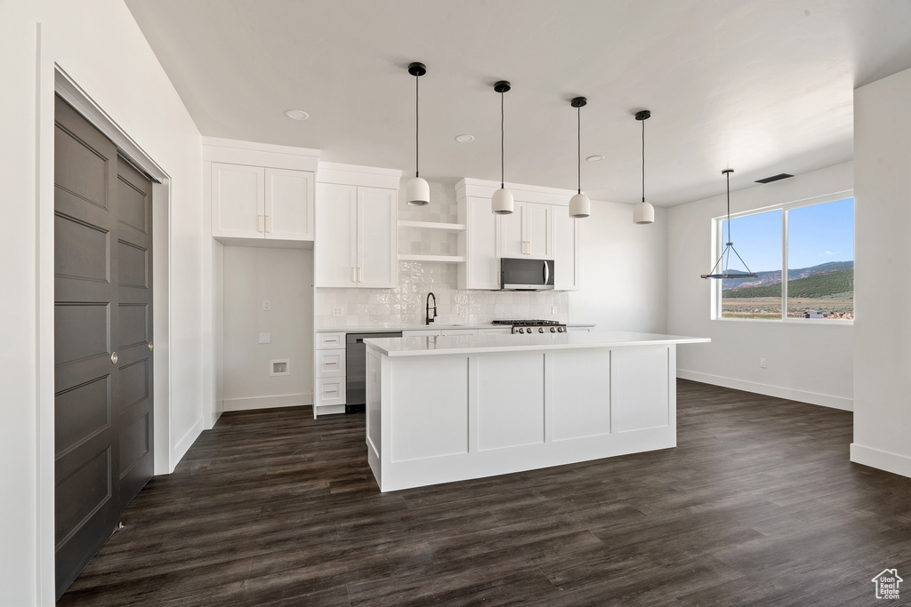 Kitchen with open shelves, stainless steel appliances, white cabinetry, backsplash, and light countertops