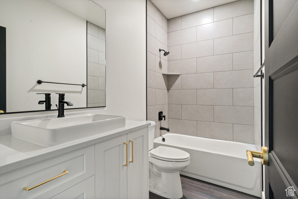 Full bathroom featuring vanity, wood finished floors, and washtub / shower combination