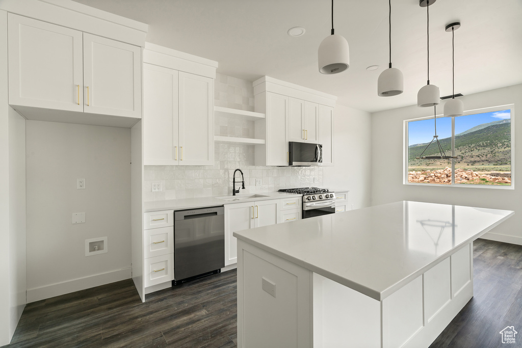 Kitchen featuring stainless steel appliances, open shelves, backsplash, a center island, and white cabinets