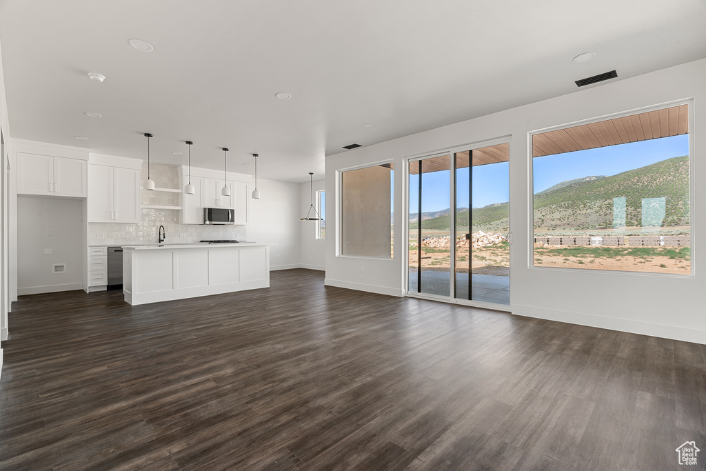 Unfurnished living room featuring a mountain view and dark wood-style flooring
