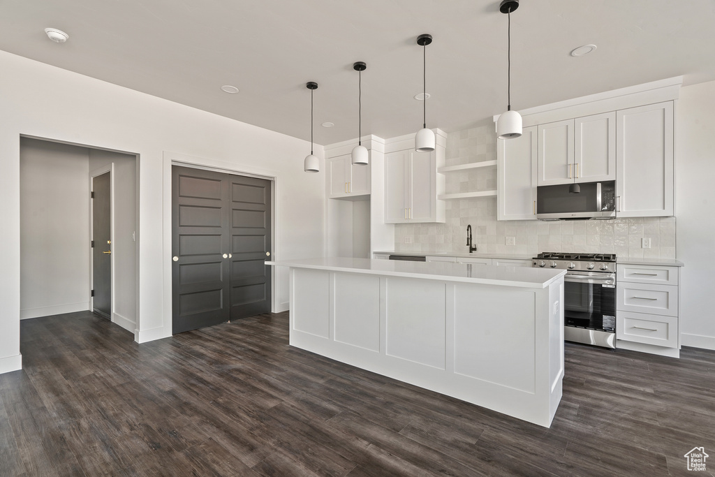 Kitchen featuring appliances with stainless steel finishes, tasteful backsplash, dark wood finished floors, white cabinets, and light countertops