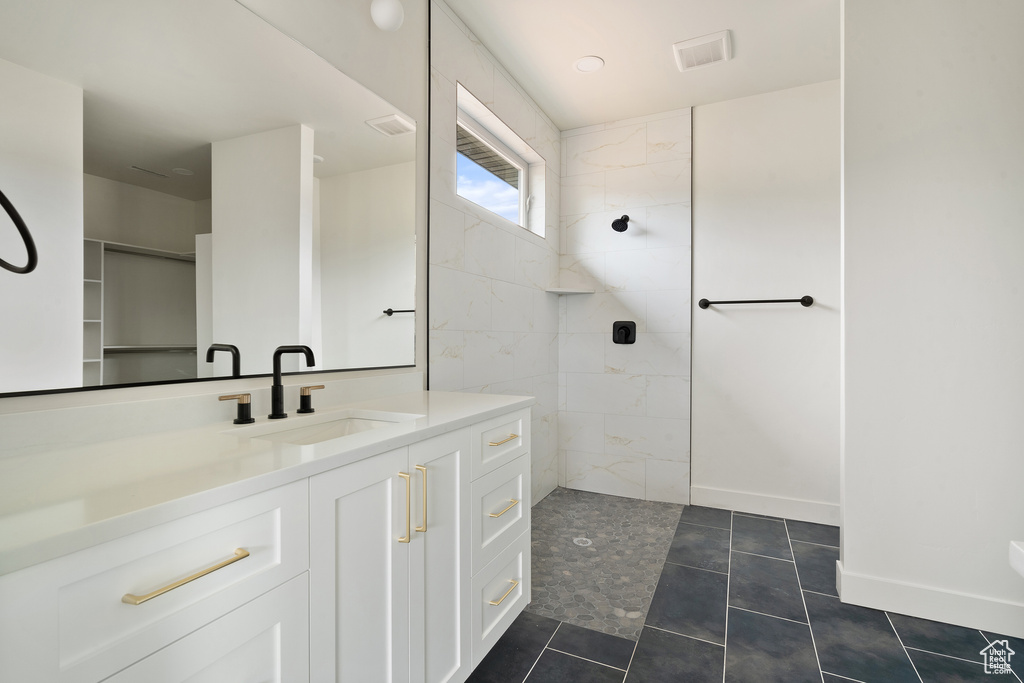 Full bathroom featuring a walk in shower, vanity, and tile patterned flooring