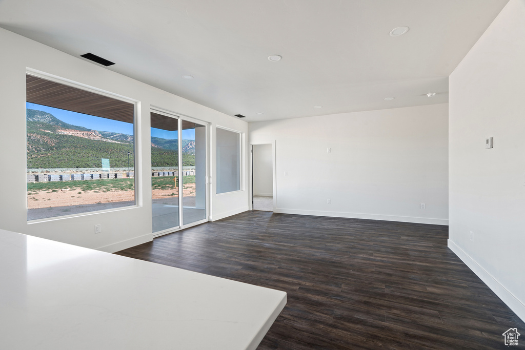 Spare room with a mountain view, dark wood-type flooring, and recessed lighting