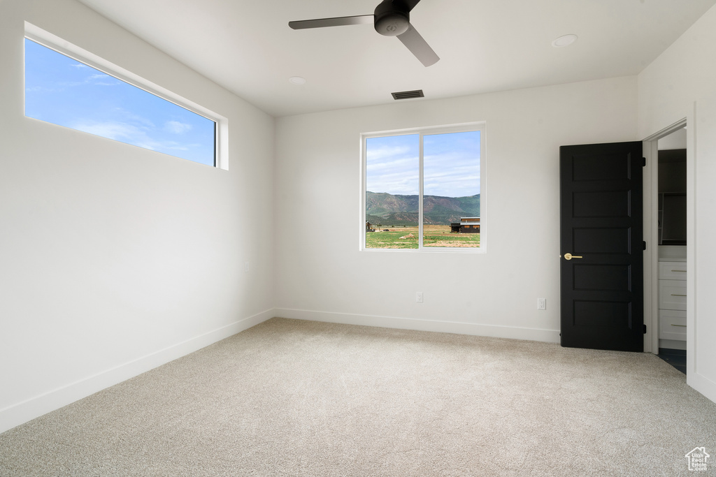 Carpeted empty room featuring a ceiling fan and a mountain view