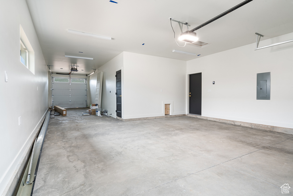 Garage featuring electric panel, a garage door opener, and baseboard heating