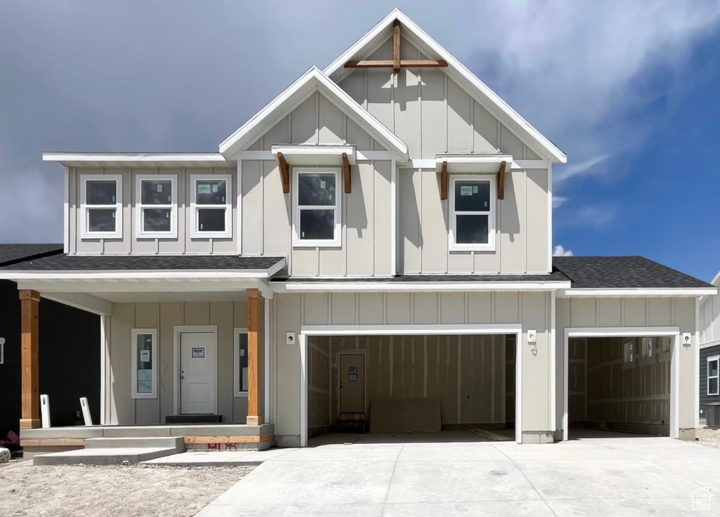 View of front of property with board and batten siding, a shingled roof, a porch, and driveway