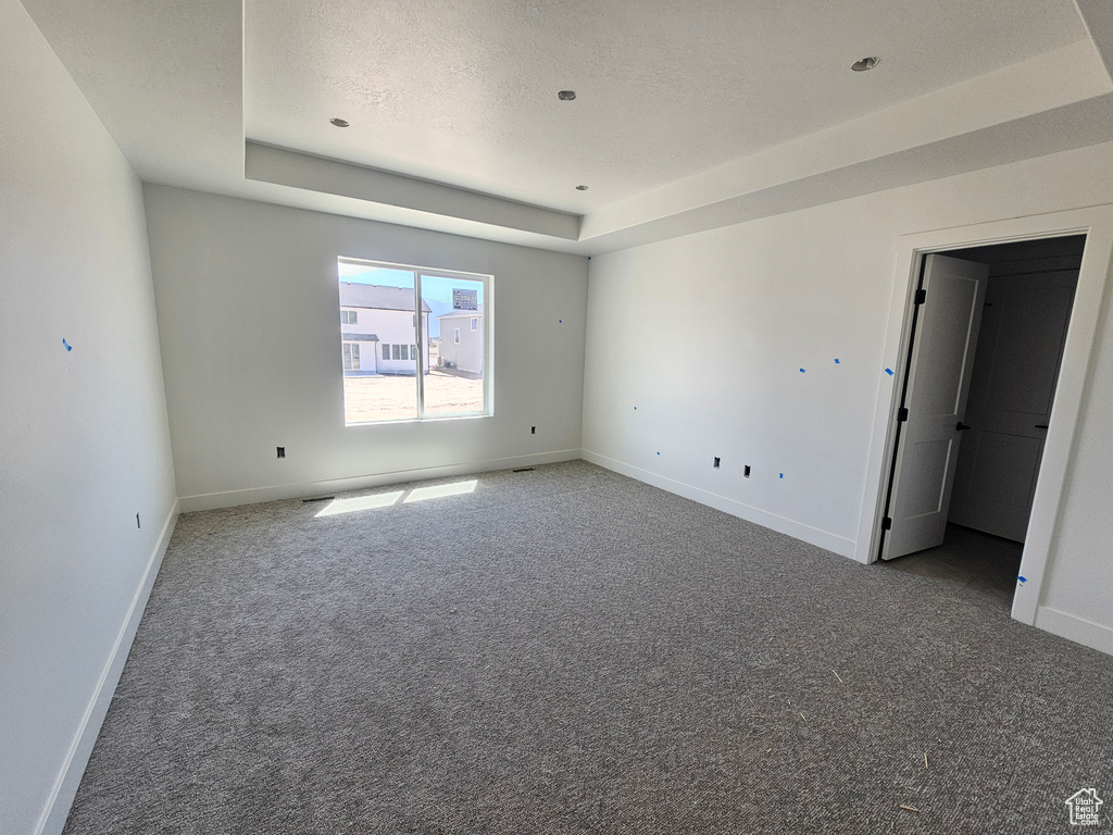 Unfurnished room with carpet flooring and a tray ceiling