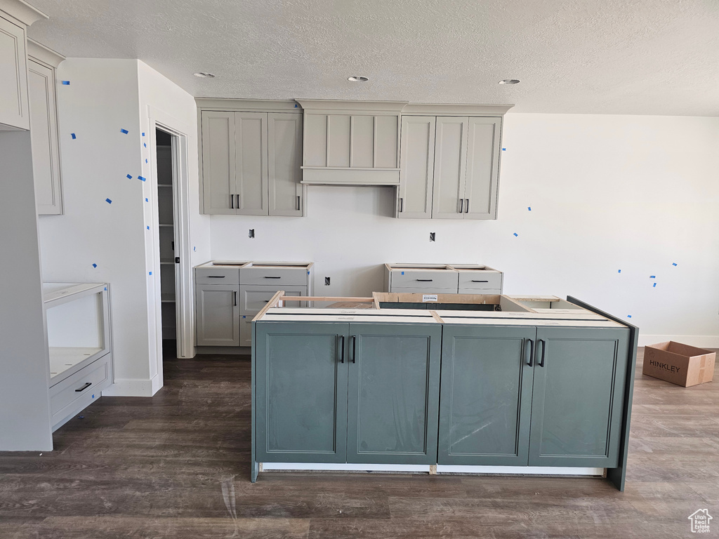 Kitchen with a center island, a textured ceiling, dark wood-style flooring, and gray cabinets